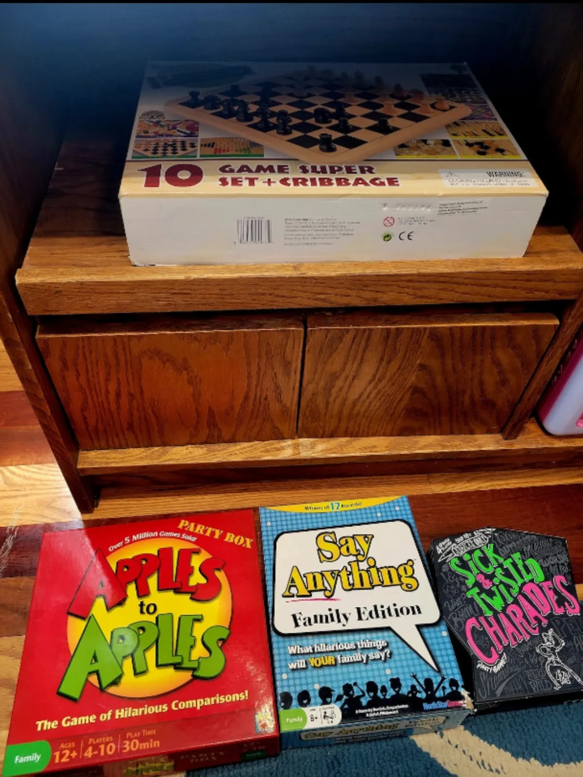 A close-up of a wooden shelf stacked with brightly colored game boxes, suggesting a variety of indoor games available for all ages. The playful arrangement hints at memorable family game nights and friendly competition beyond just the pool table.