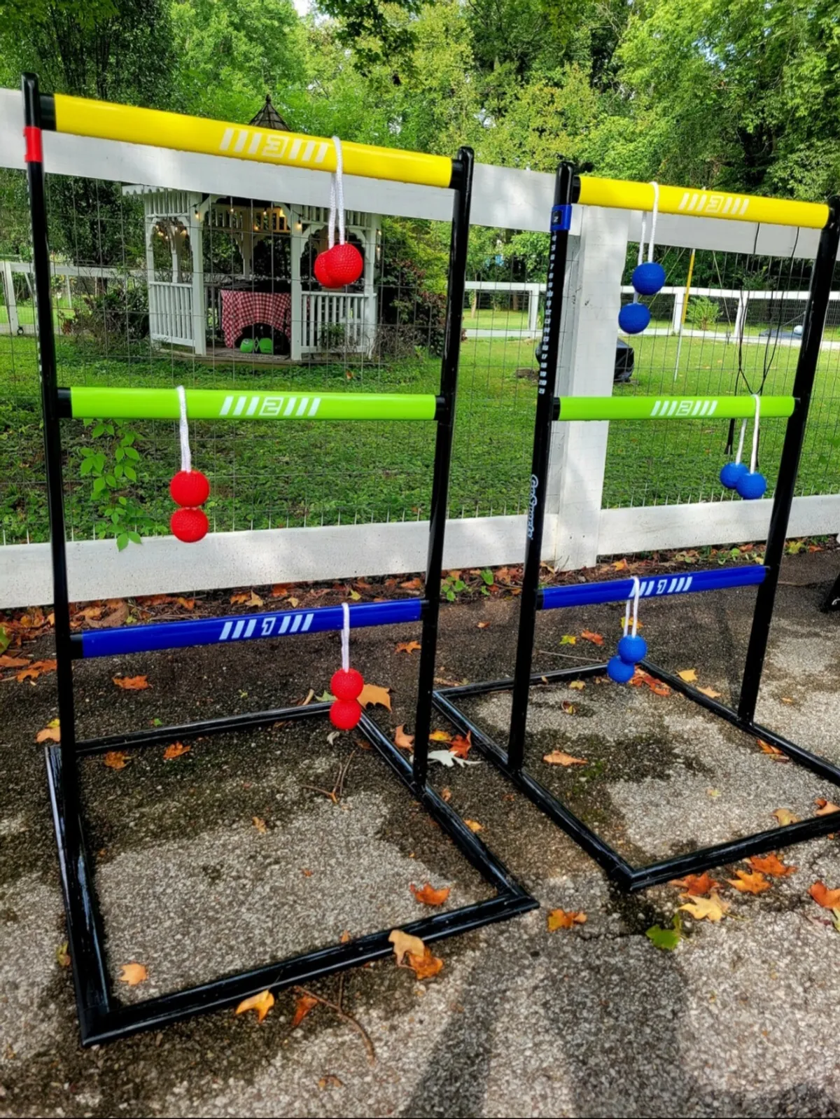 A vibrant backyard scene featuring a colorful ladder toss game positioned on green grass near a white gazebo. The image captures an outdoor play area designed for friendly competition and laughter-filled moments among family members.